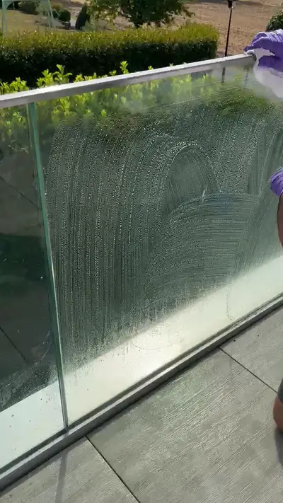 Garde-corps en verre d’un balcon couvert de mousse de nettoyage, terrasse carrelée au premier plan