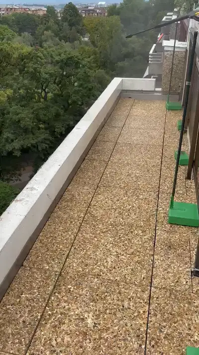 Terrasse en toiture avec garde-corps vitrés et bande de gravier, vue sur les arbres