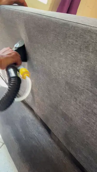 Suceur d’injection-extraction passé sur l’accoudoir d’un canapé en tissu gris